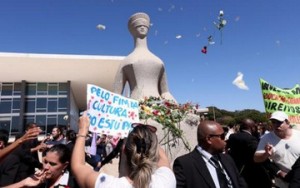 Estátua de Têmis, a deusa da Justiça, que fica em frente ao STF teve o colo coberto por flores e cartazes